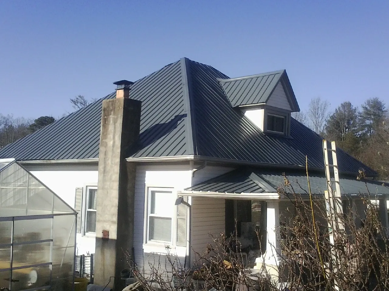 Dark blue standing seam metal roof on a white farmhouse with dormer — Slate & Tile Roof Repair by Roofing Brothers in Lily