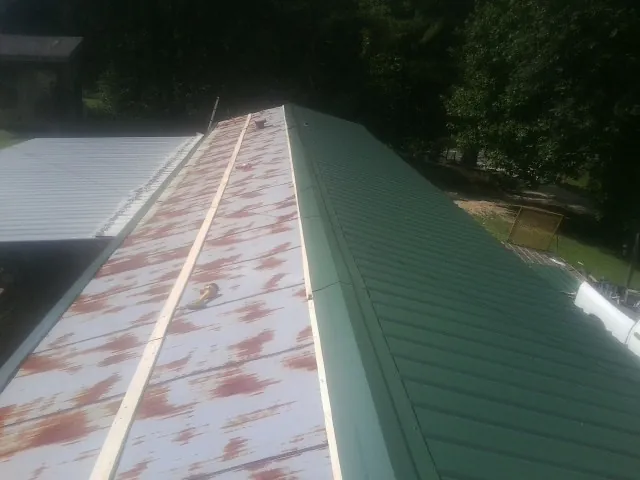 Old rusted panels beside newly installed green metal roofing — Wind Damage Roof Repair by Roofing Brothers in Lily