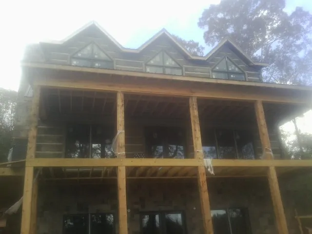 Dormers and porch framing on a large log home under construction — Roof Coating work by our crew in Lily