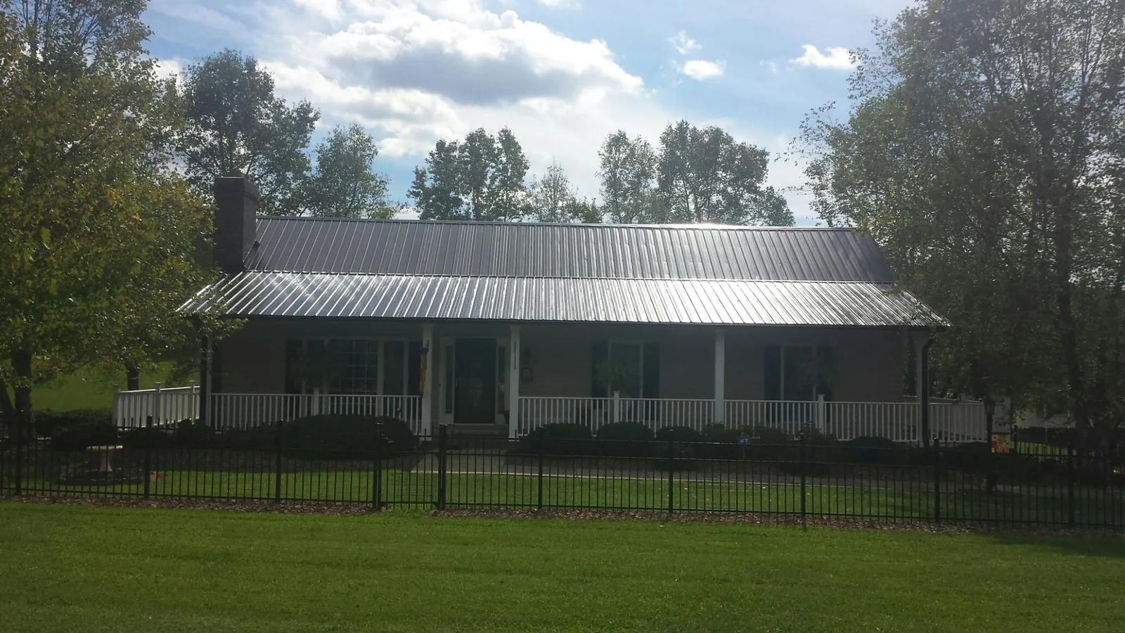 Gray metal roof on a brick ranch with a full width front porch — Gutter Guard Installation work by our crew in Lily