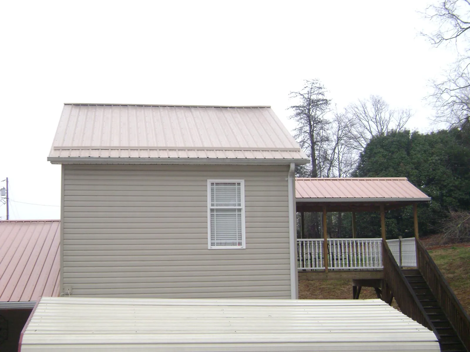 Tan metal roofs on a two story addition and attached porch, from a Roof Replacement job in Lily