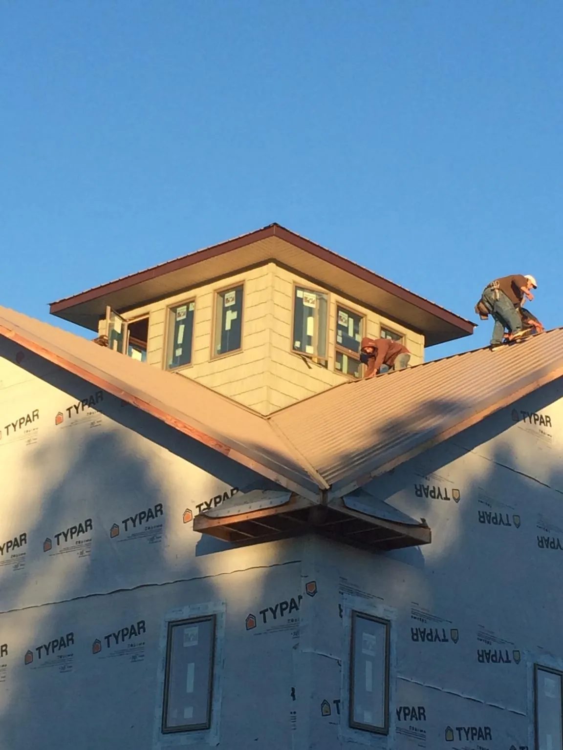 Roofers working around a rooftop cupola on a new metal roof at sunset — Roof Waterproofing in Lily by Roofing Brothers